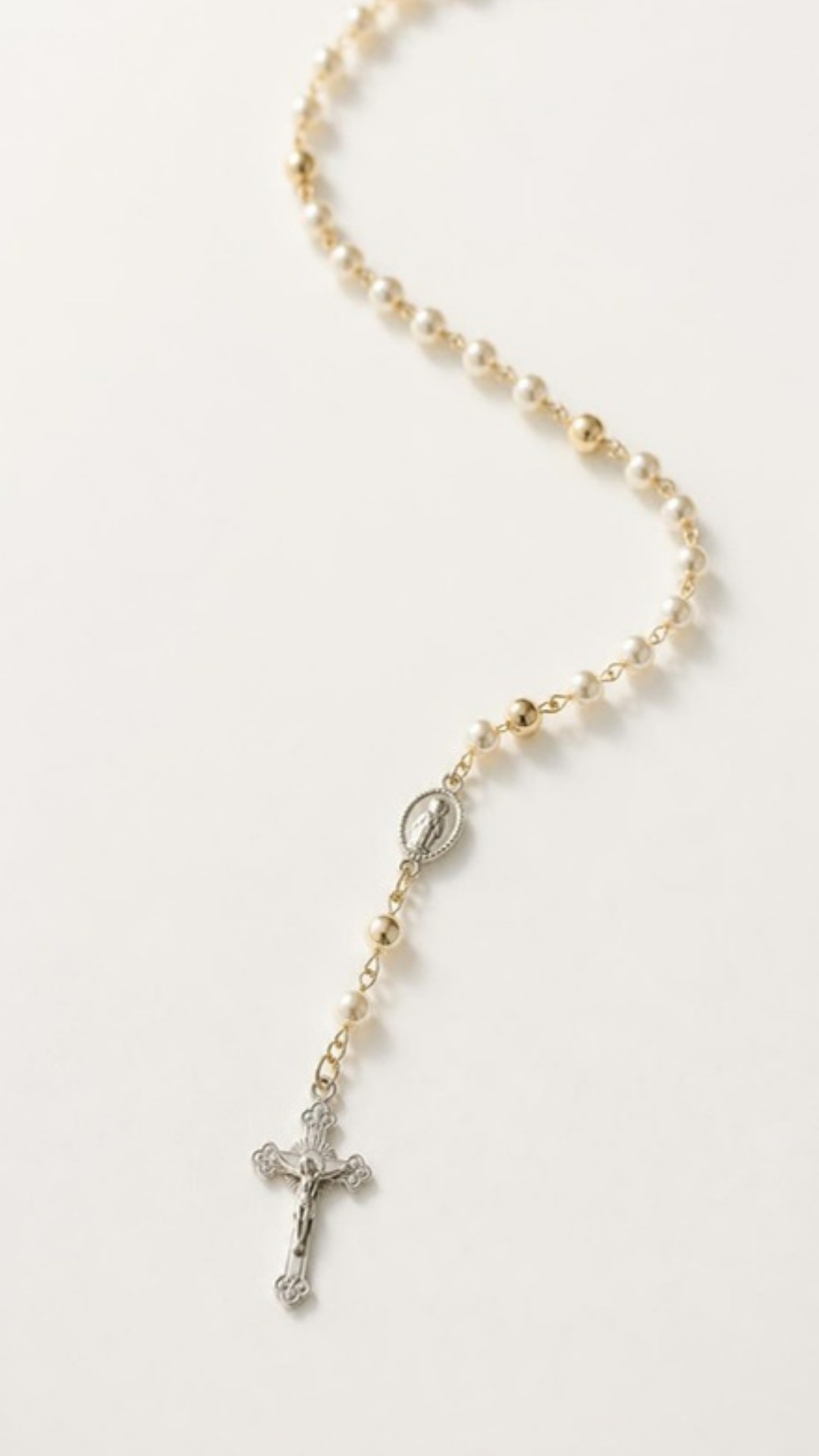 AI-generated illustration: a rosary of pearl and gold beads with a silver crucifix on an ivory background. Minimalist design.